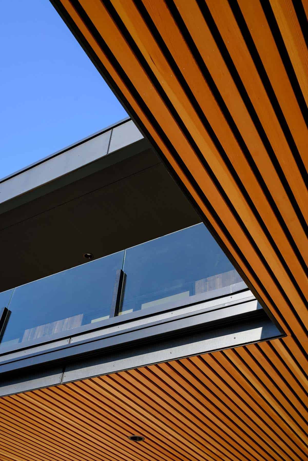 Angular wood slat ceiling frames glass balcony railing detail below
