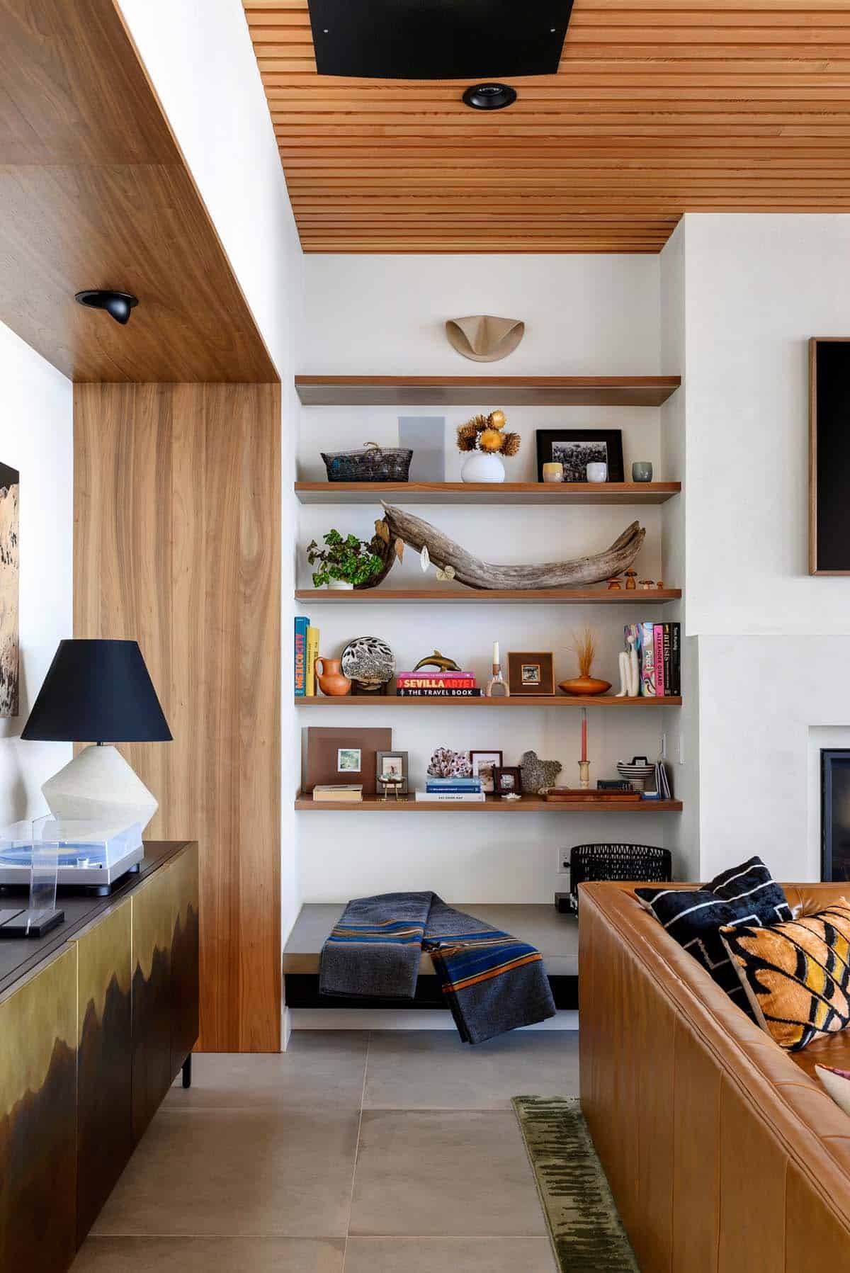 Built-in shelving displays driftwood books and travel keepsakes above bench