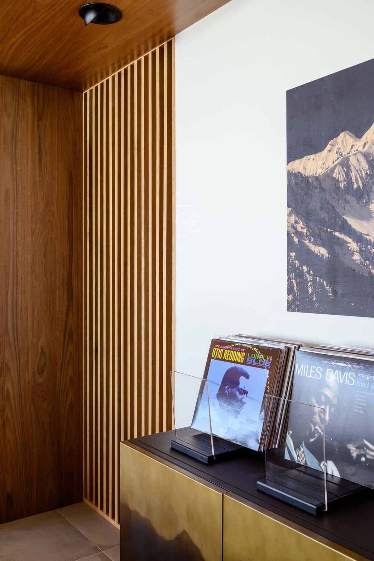 Vinyl records lean beside mountain print and wood slat wall