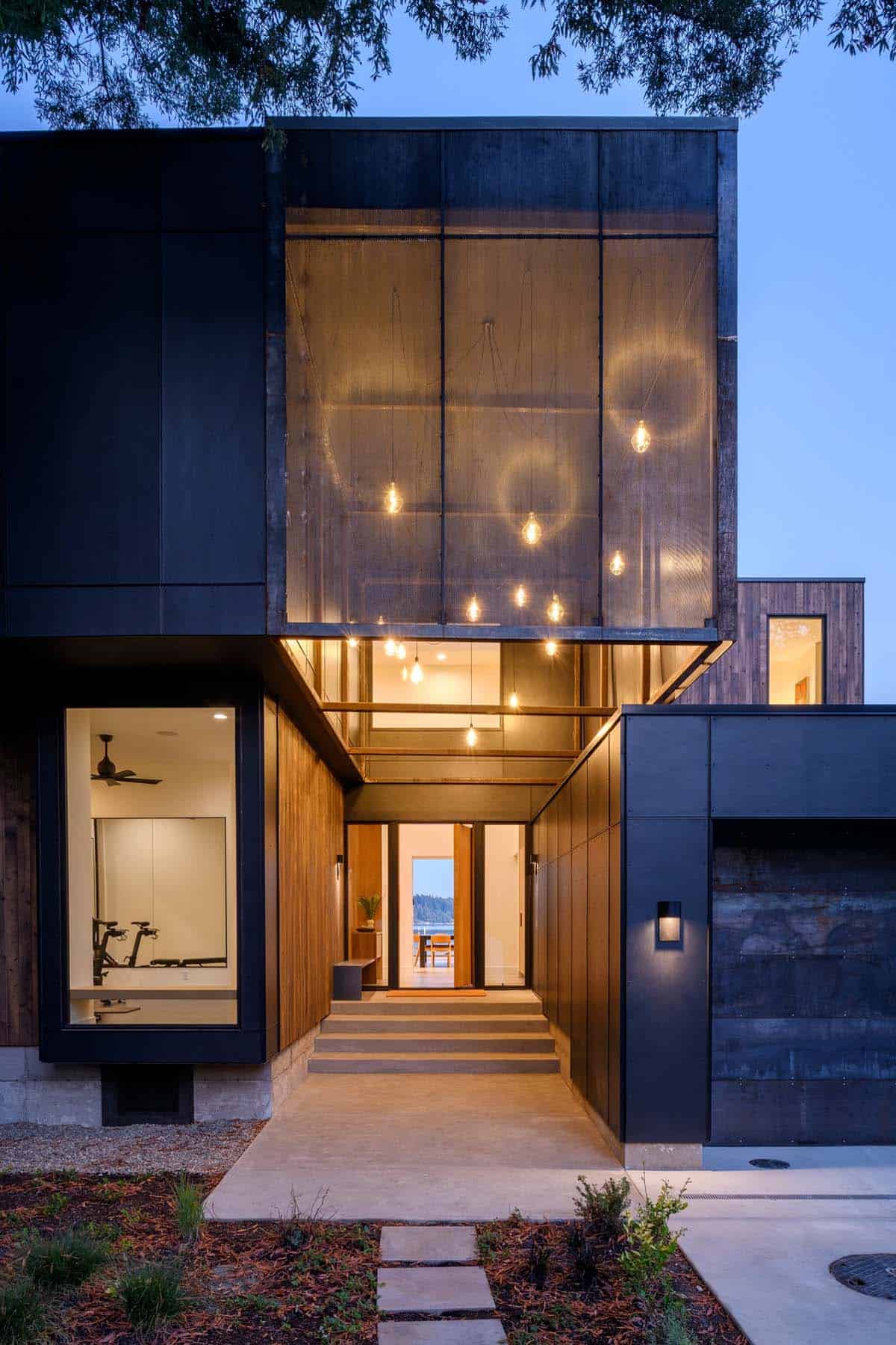 Black metal facade illuminated at dusk with glowing entry path