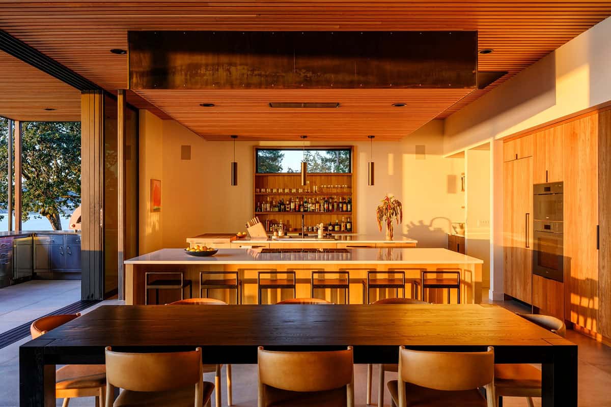 Wood dining table faces kitchen bar and glowing sunset light