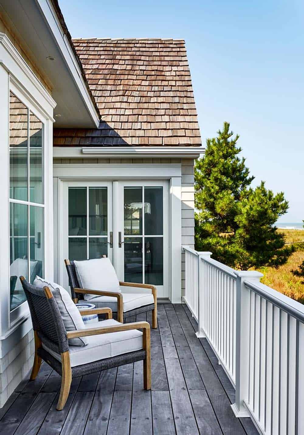 Private balcony nook beneath cedar shake roofline and pines