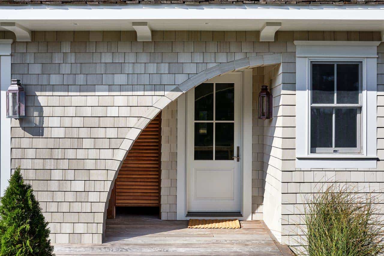 Arched wood entry door flanked by copper lantern sconces
