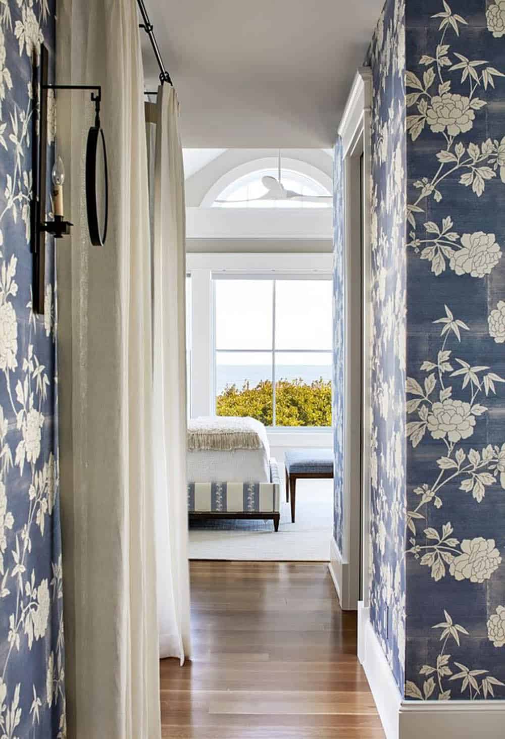 Floral wallpapered hallway opening to an ocean-view bedroom