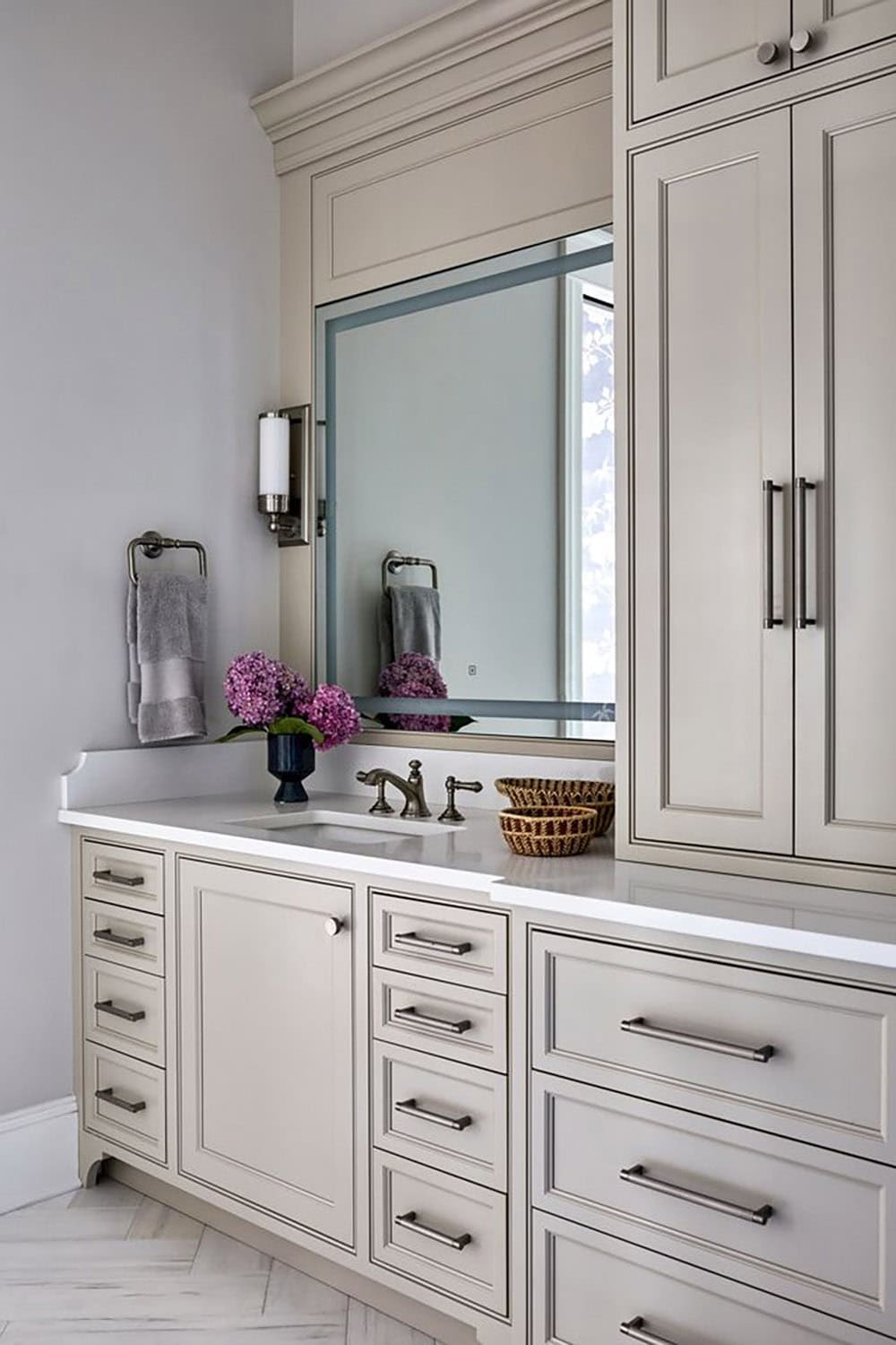Gray bathroom vanity with brass hardware and fresh flowers