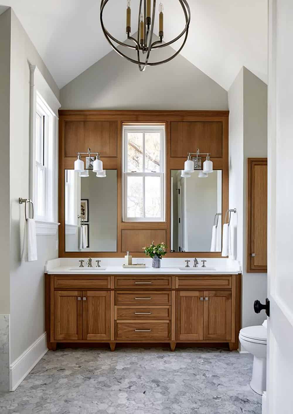 Double vanity bathroom with wood cabinetry and orb chandelier