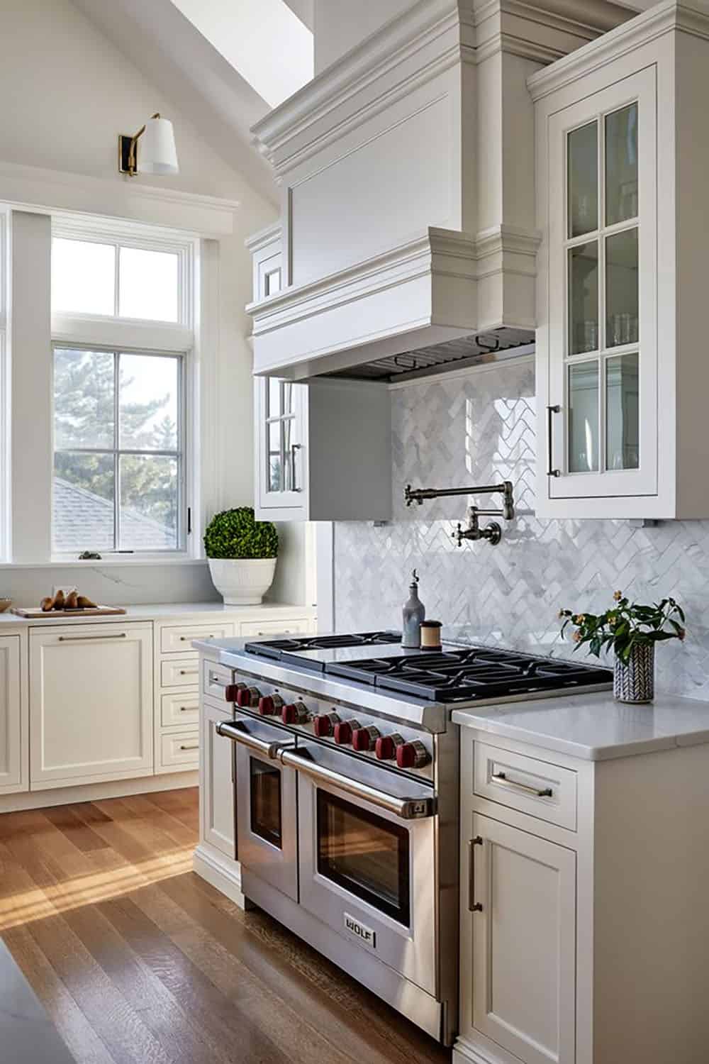 Wolf range and hood beneath herringbone marble backsplash tile
