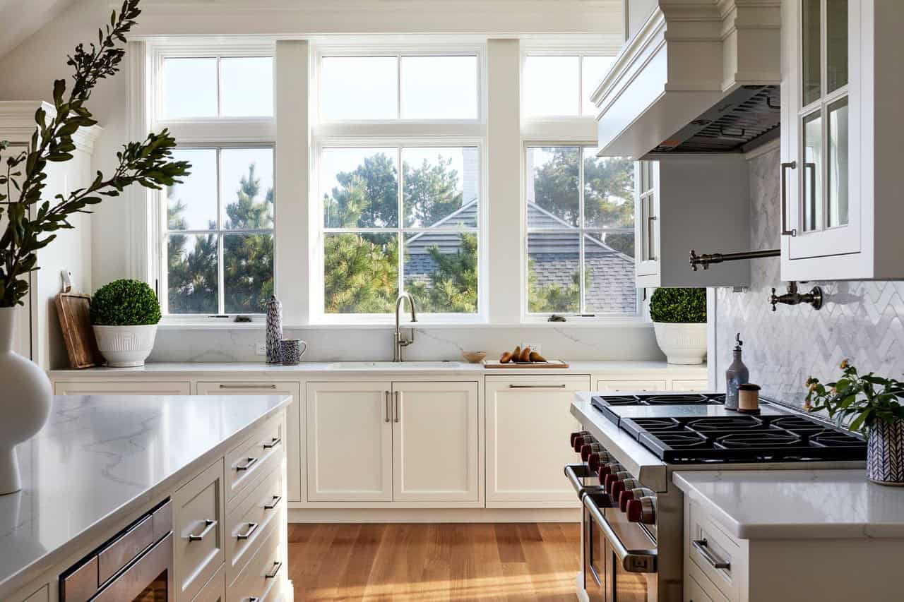 Kitchen island view toward gas range and windowed sink wall