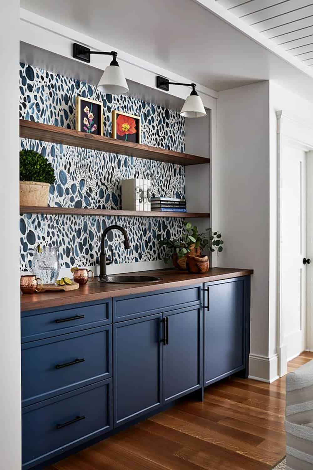 Navy wet bar with patterned wallpaper and floating wood shelves