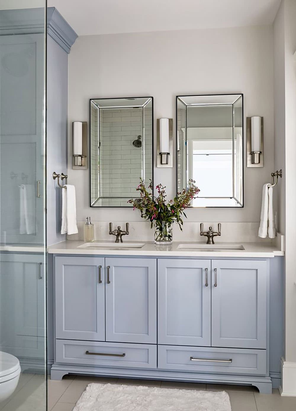 Dual mirror vanity in a powder-blue bathroom with sconces