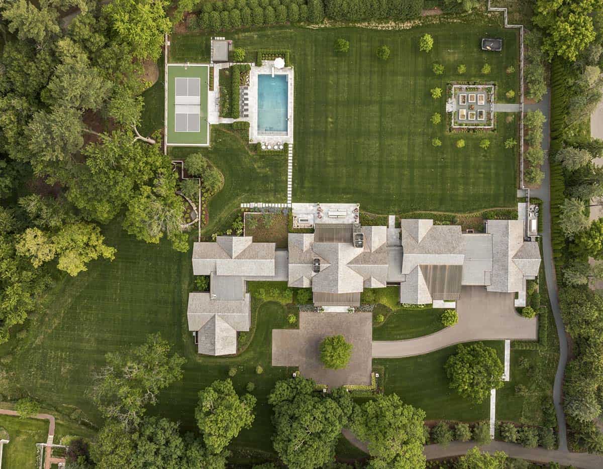 Aerial view of the home's roofline, pool, tennis court, and manicured grounds