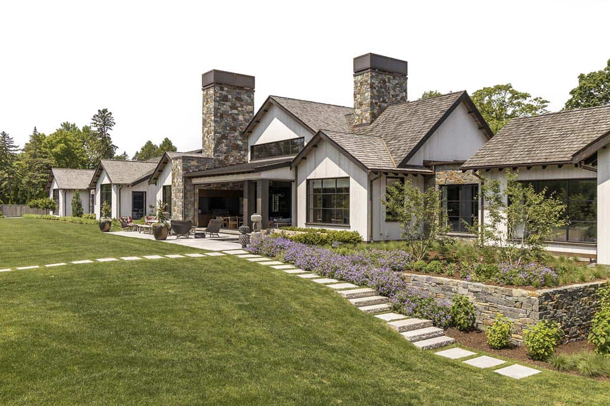 Rear exterior with stone chimneys, covered outdoor living area, and stone retaining wall