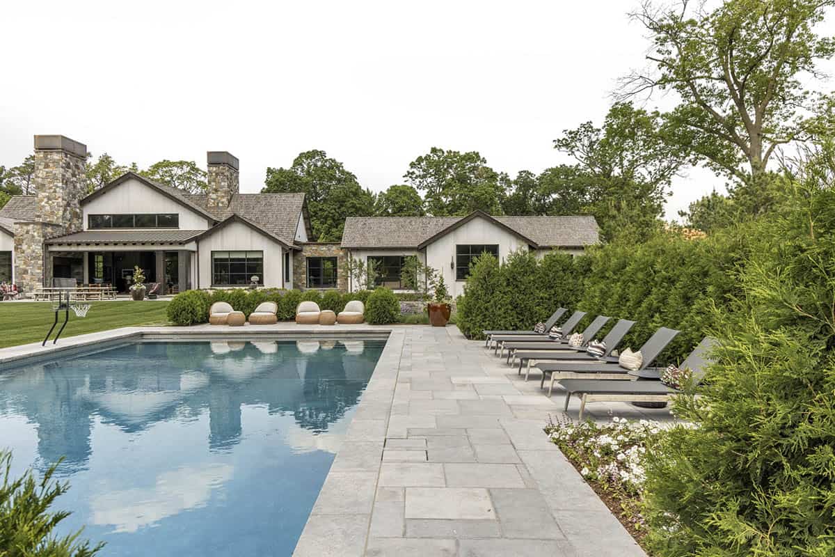 Pool area with lounge chairs, stone chimneys, and covered outdoor living space in view
