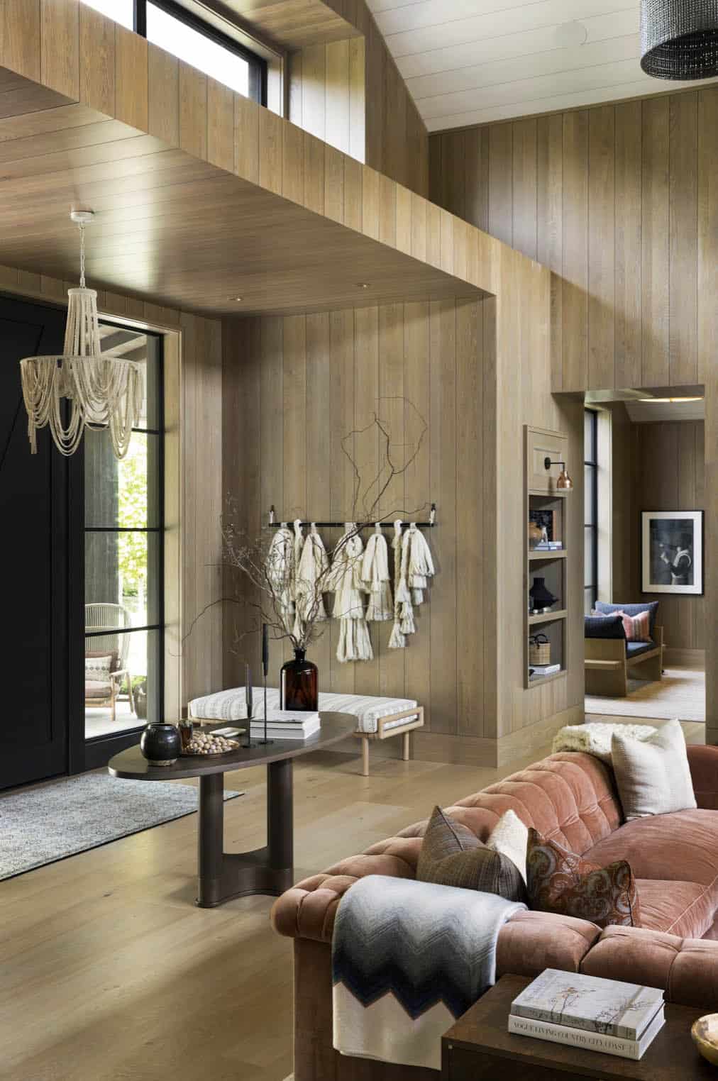 Entryway with wood-paneled walls, fringe wall hanging, and velvet sofa