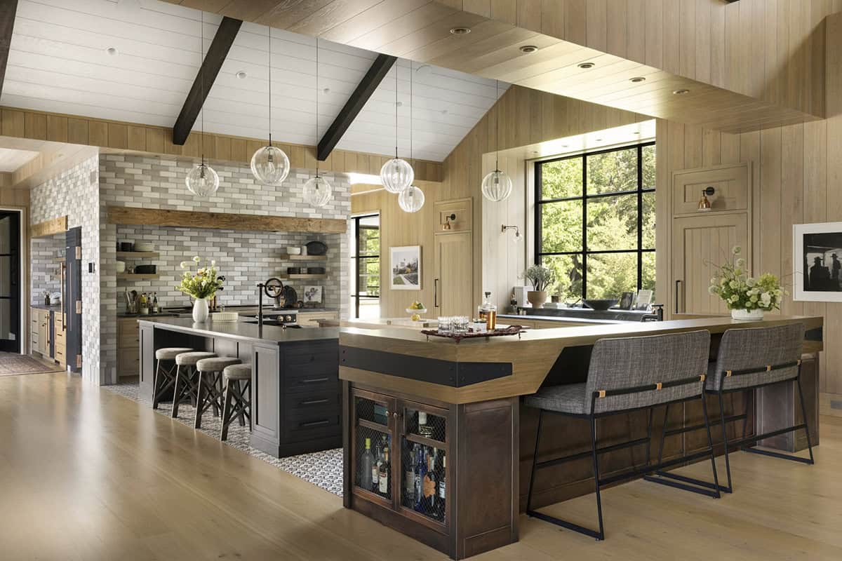 Kitchen with dual islands, glass globe pendants, tile range hood, and wet bar with wine fridge