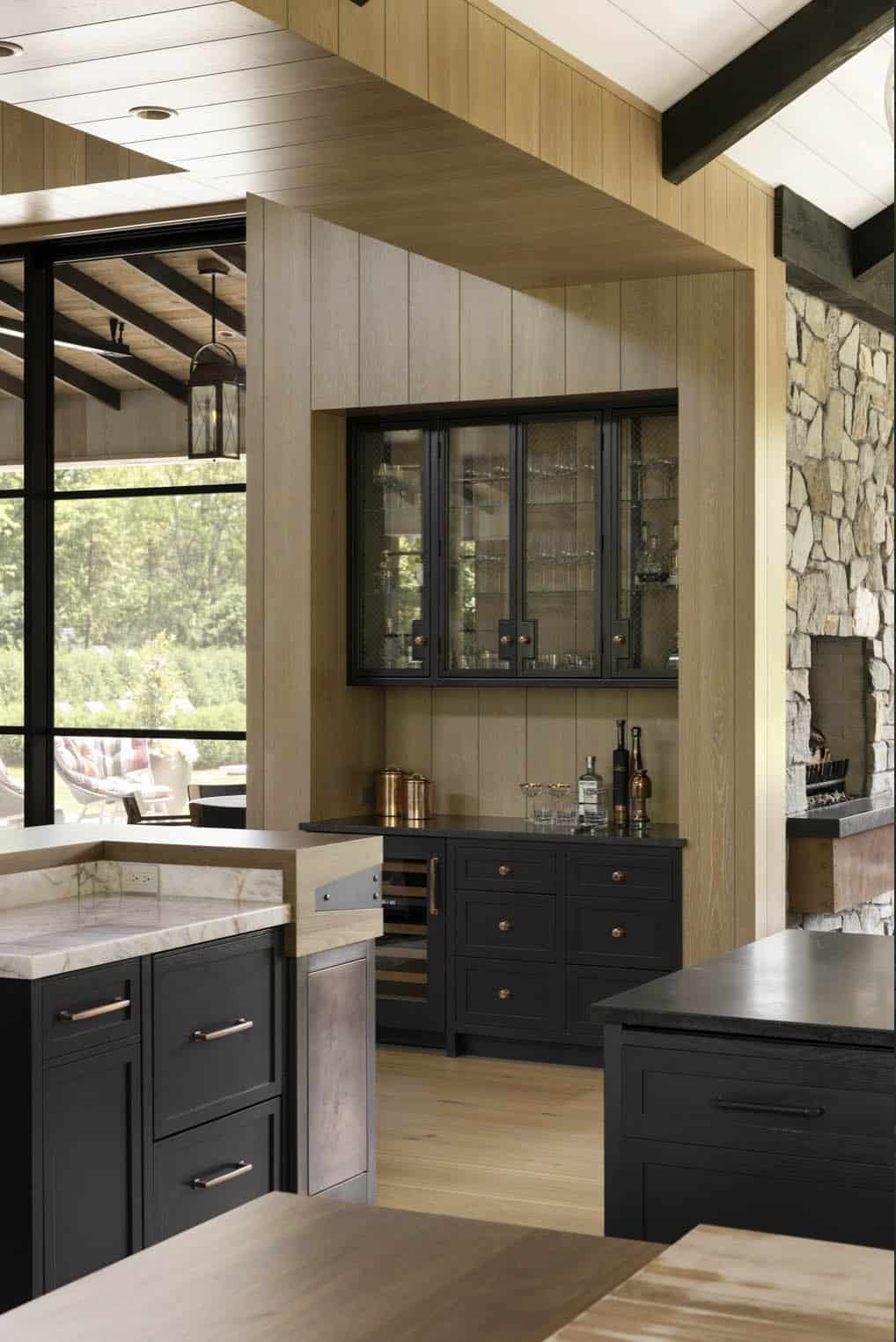 Wet bar nook with glass-front cabinet, wine fridge, and stone fireplace visible alongside