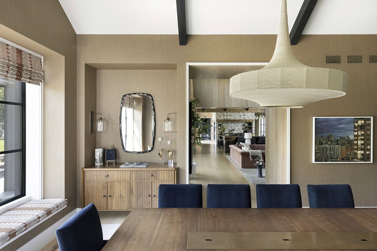 Dining area with woven pendant light, navy chairs, and view into the living room beyond