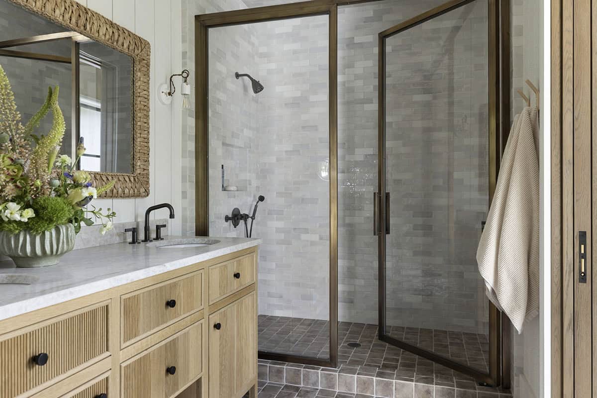 Bathroom with fluted wood vanity, marble countertop, and glass-enclosed tiled shower
