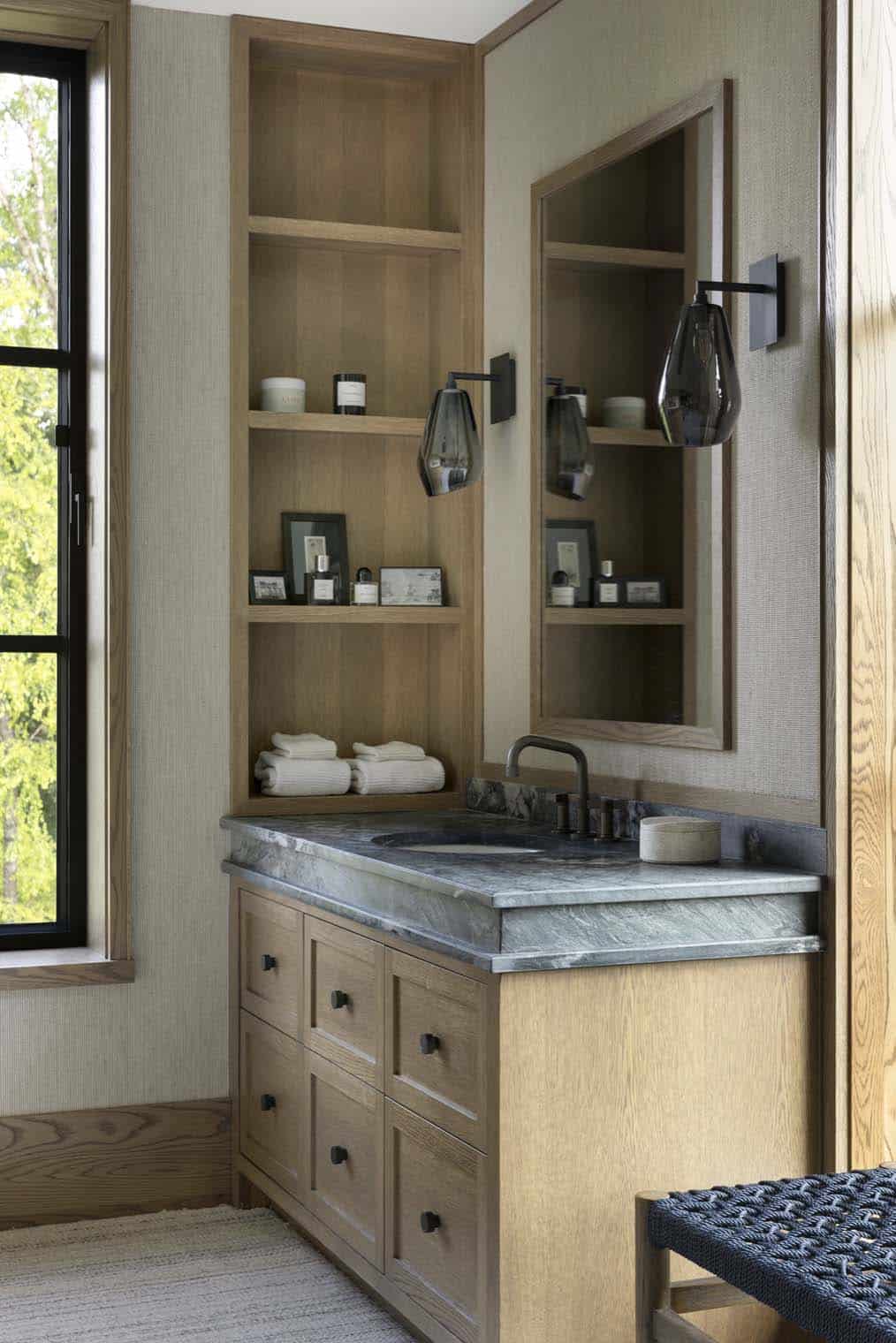 Bathroom vanity nook with open shelving, marble countertop, and glass teardrop sconces