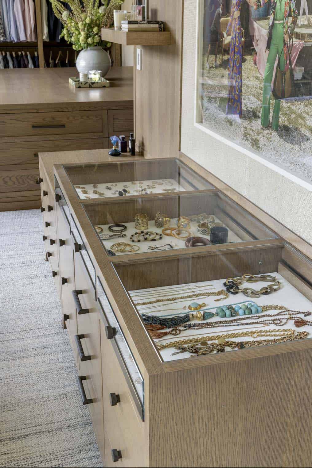 Closet jewelry island with glass display drawers holding rings, bracelets, and necklaces