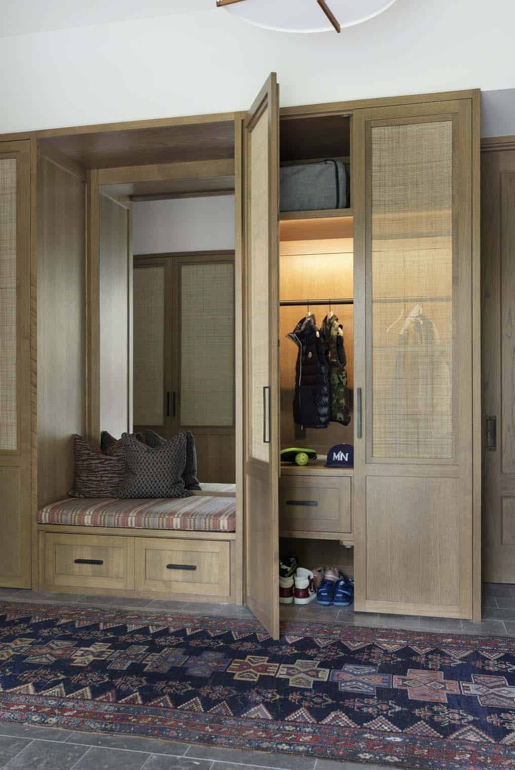 Mudroom cubby with open cane-front door revealing coat hooks, cap, and storage