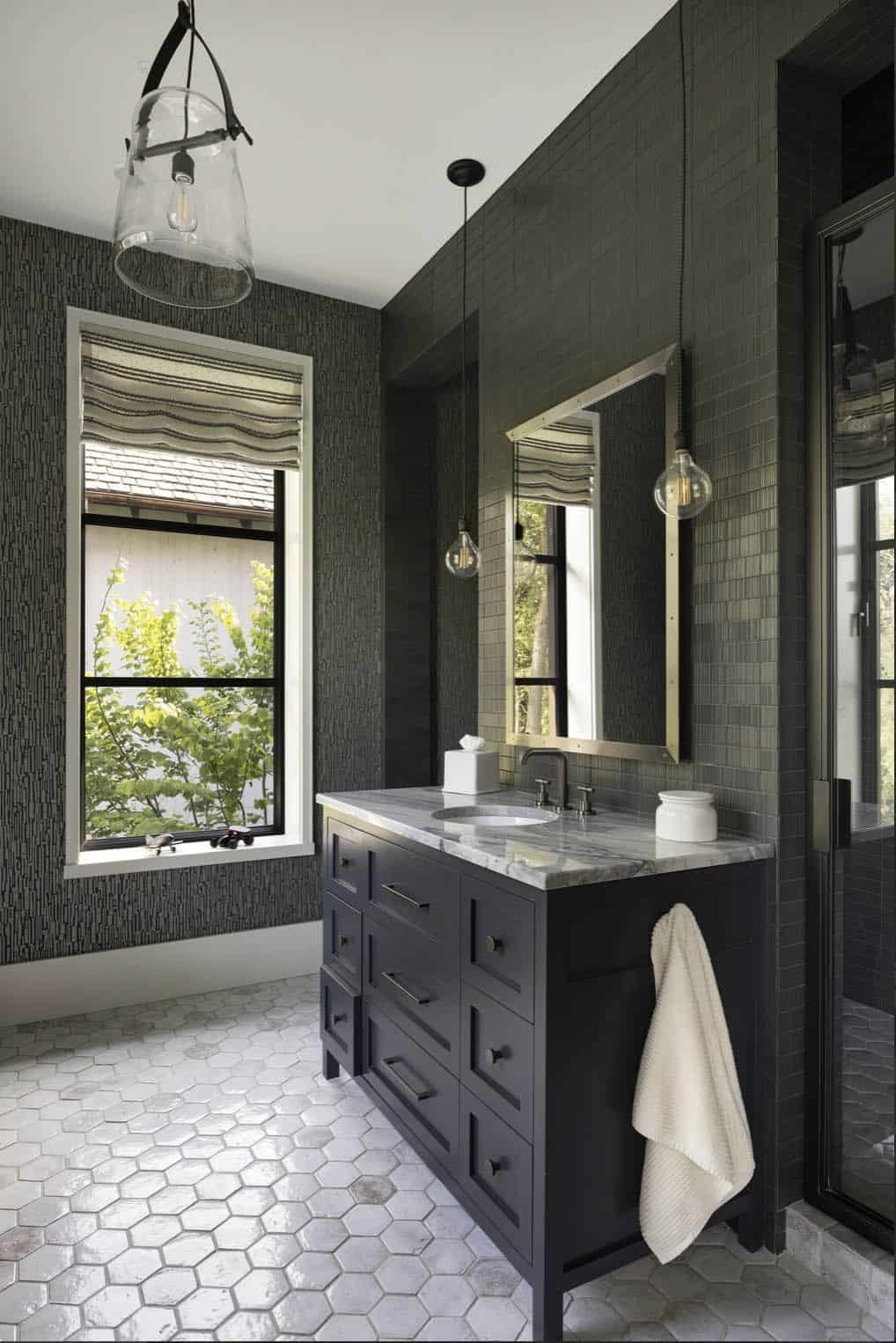 Bathroom with dark textured wallpaper, navy vanity, hexagon floor tile, and pendant lighting