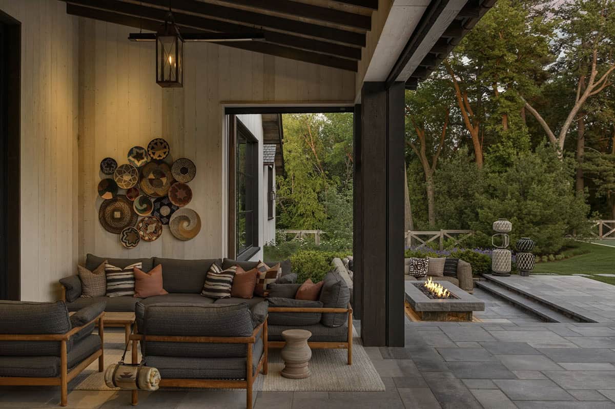 Covered outdoor lounge with sectional seating, basket wall art, and view to fire pit terrace
