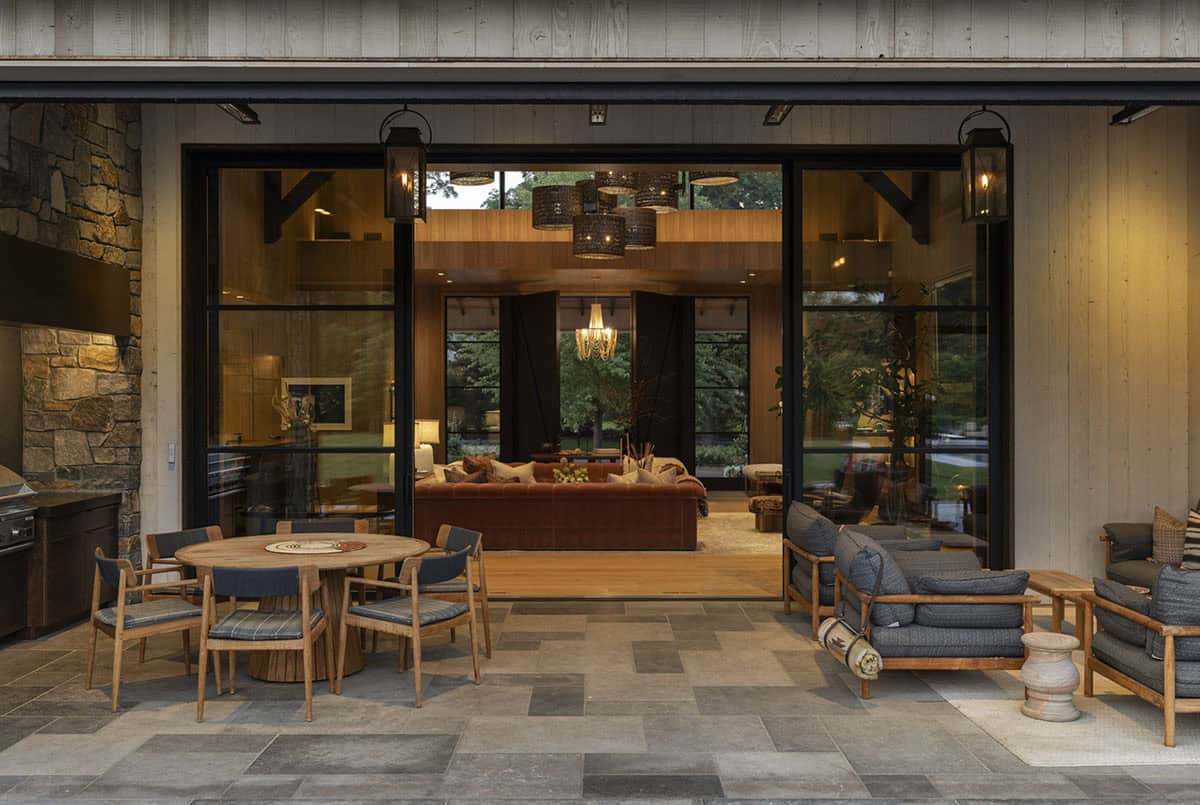 Patio dining and lounge area viewed through open glass doors into the wood-paneled great room