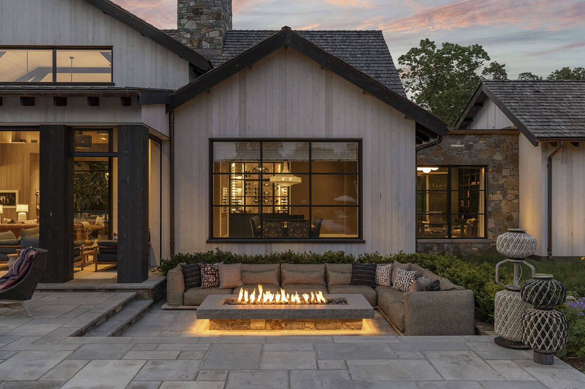 Rear exterior at twilight showing fire pit lounge, illuminated wine room window, and gabled facade