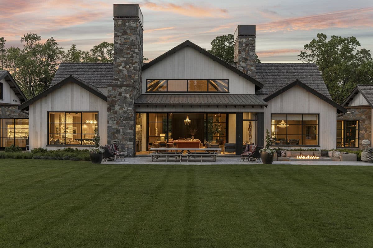 Rear facade at twilight showing covered patio, outdoor dining table, and fire pit lounge