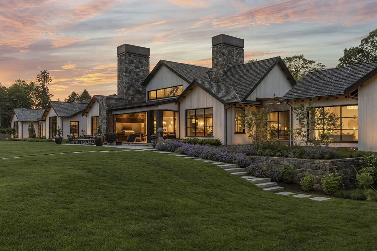 Side elevation at sunset with covered outdoor kitchen, dining area, and landscaped steps