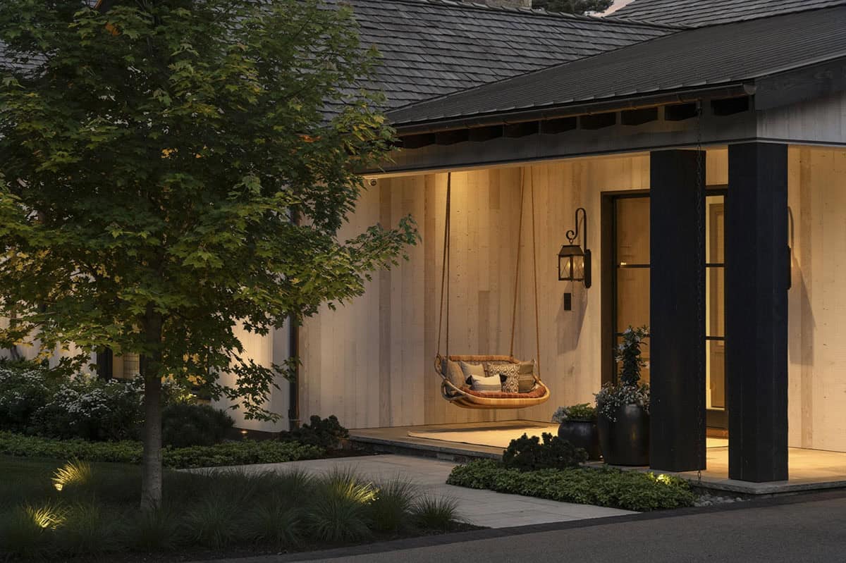Close-up of covered porch swing and entry door illuminated at dusk