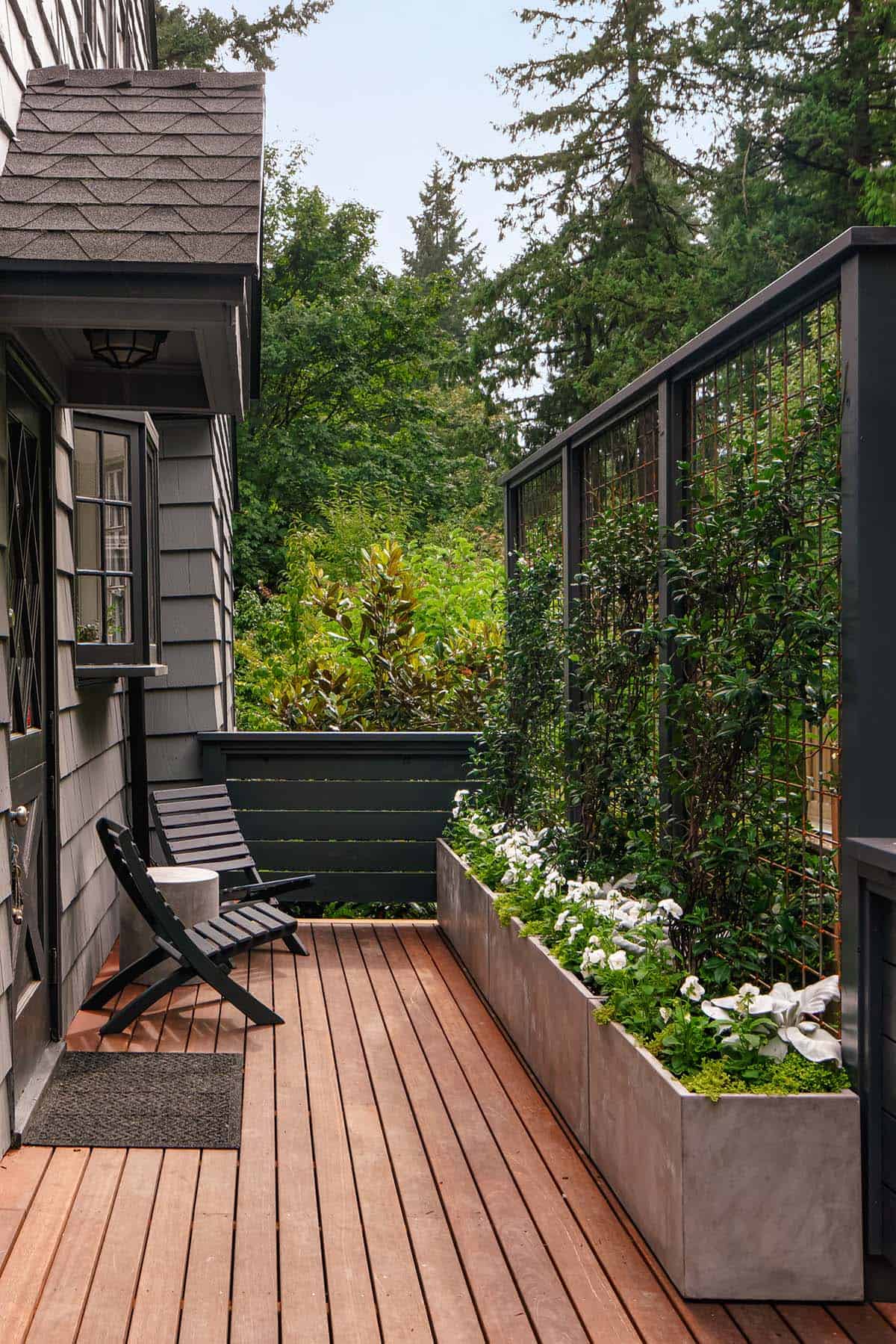 Narrow wood deck in Portland, Oregon with black folding chairs, concrete planters, and climbing vine trellis
