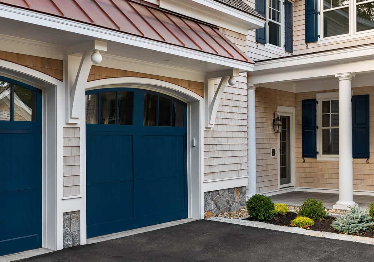 Three-car garage with navy carriage-style doors and copper standing-seam roof