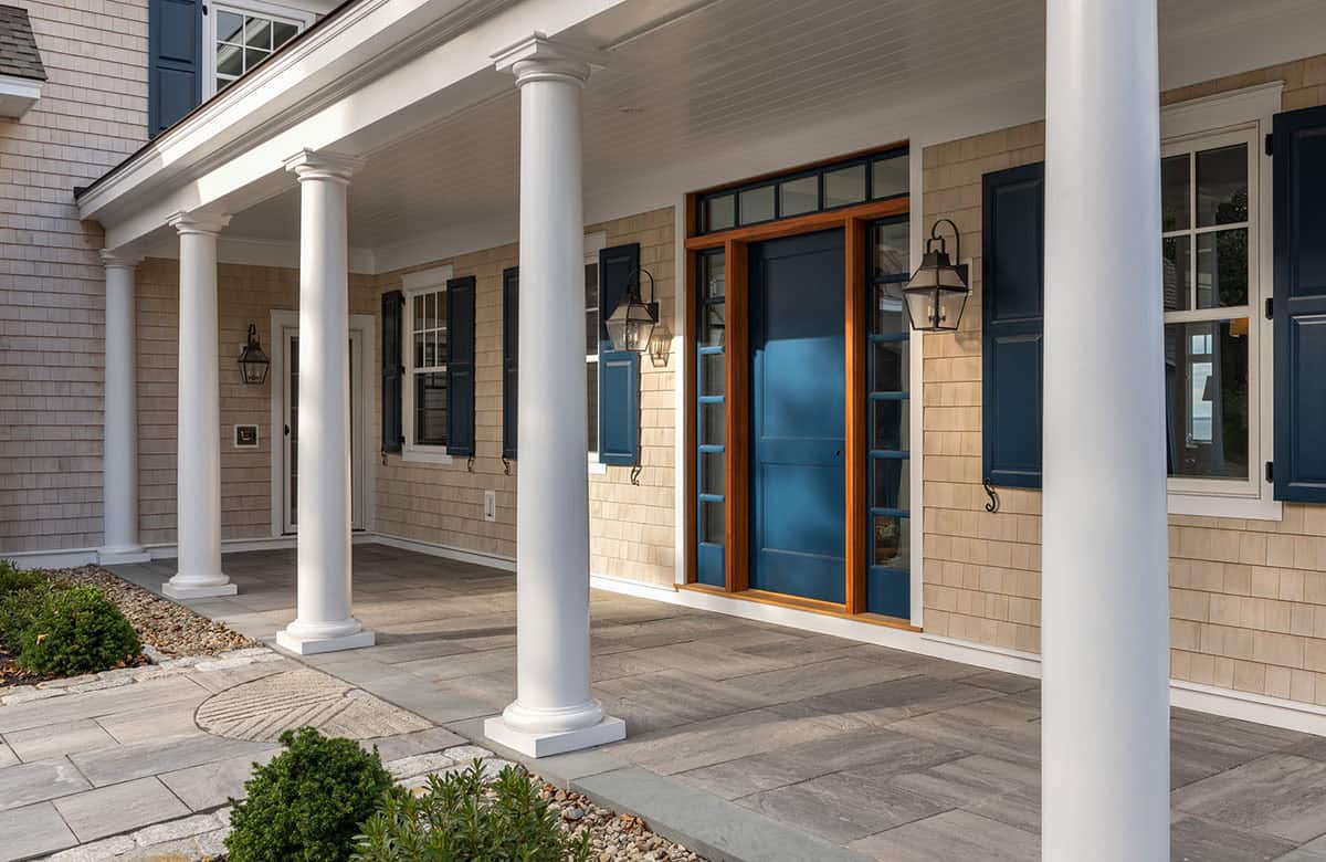 Covered front porch with white columns and navy blue front door