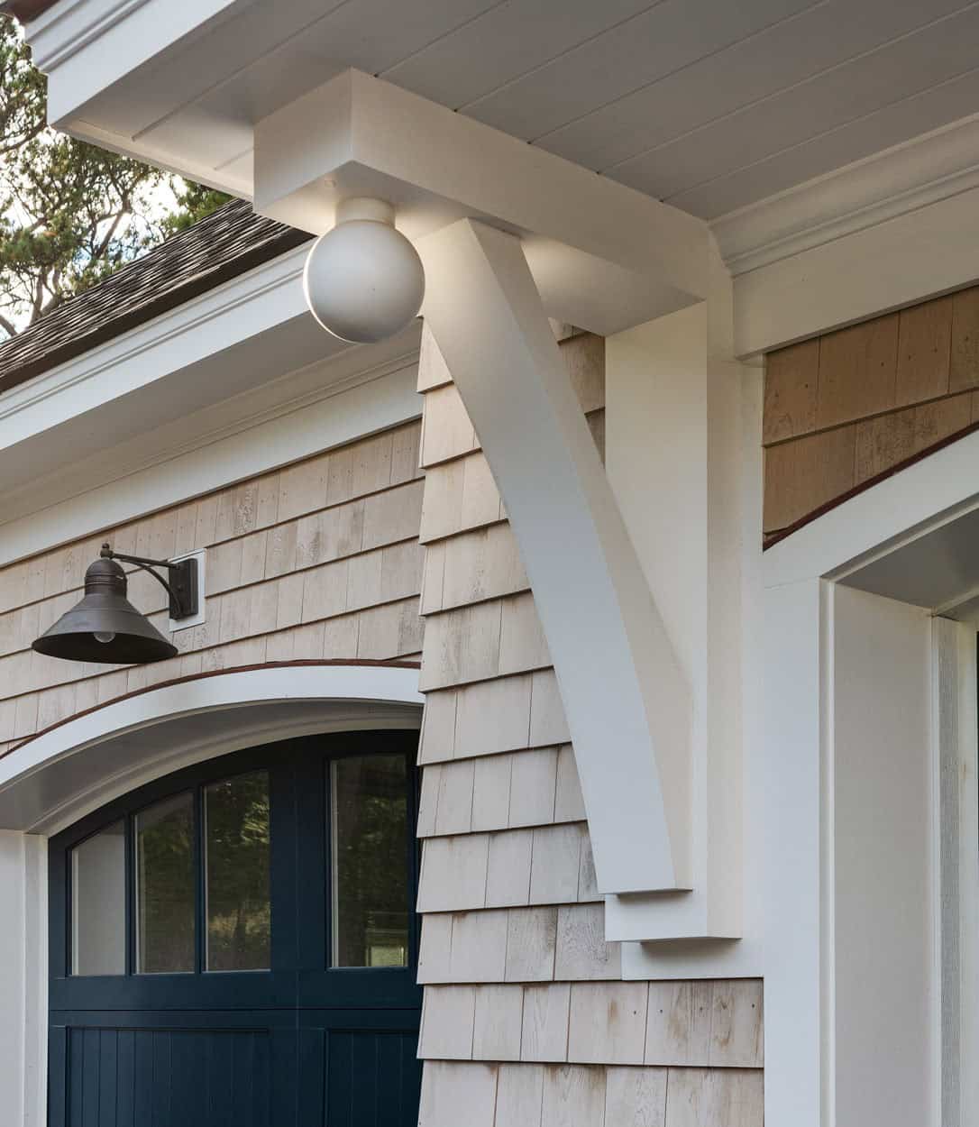 Detail of white timber bracket and globe light under copper roof eave