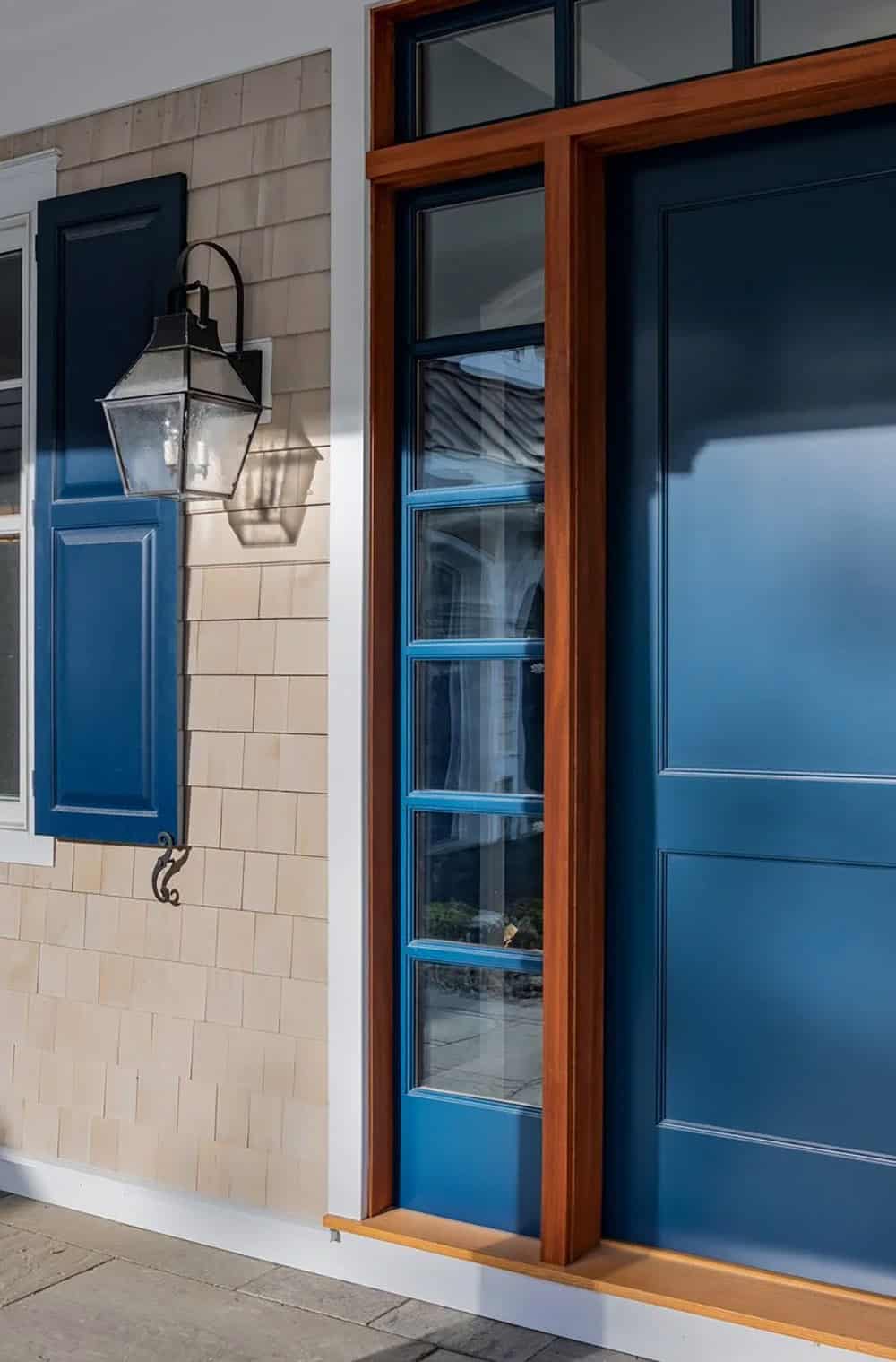 Close-up of navy front door with mahogany trim and lantern sconce