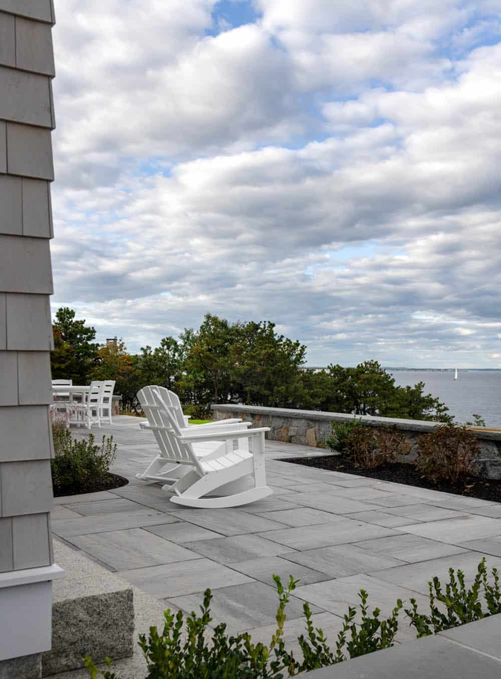 Bluestone patio with white Adirondack rocking chairs overlooking the ocean
