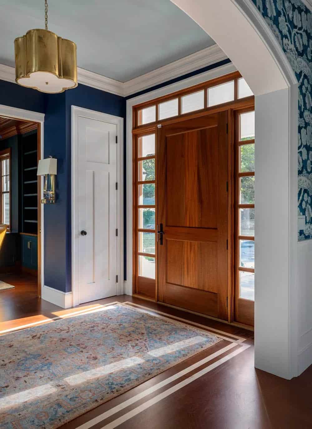Entryway with navy walls, wood front door, and patterned wallpaper
