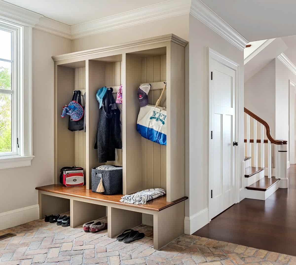 Mudroom with built-in wood lockers, bench, and brick-patterned floor