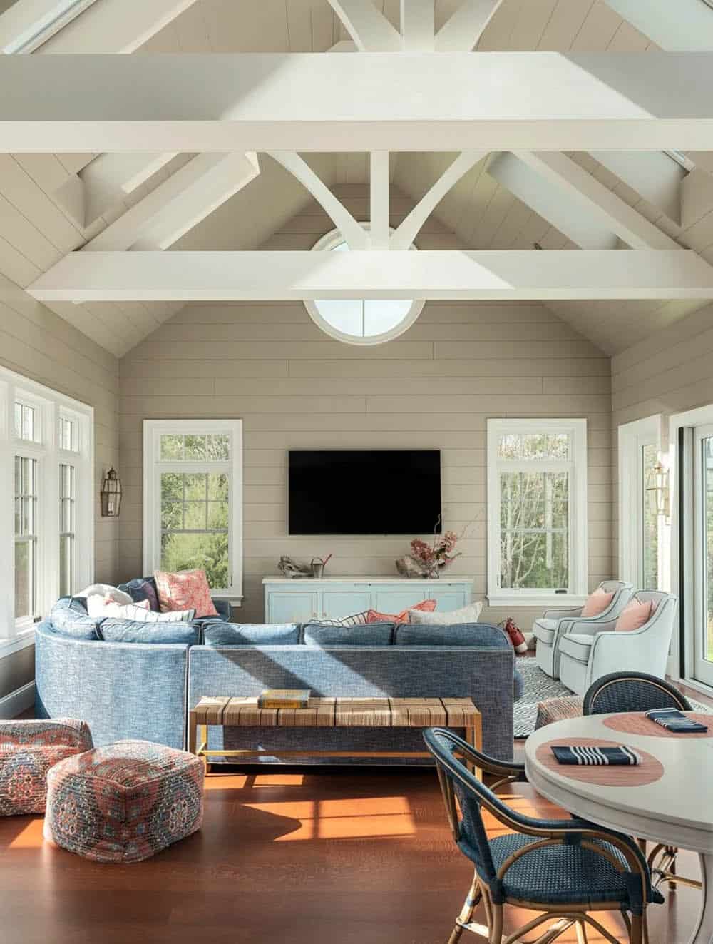 Vaulted sunroom with exposed white beams and blue sectional sofa