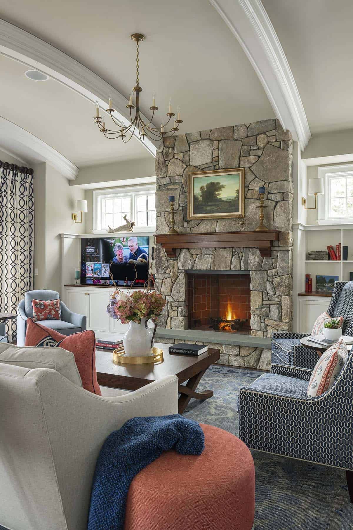 Living room with stone fireplace, TV, and blue-and-coral upholstered chairs