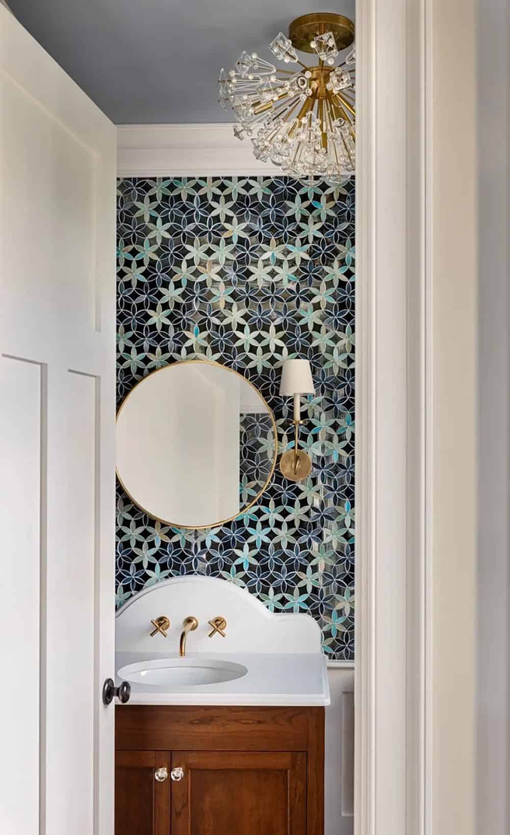 Powder room with iridescent floral mosaic tile and brass sunburst light