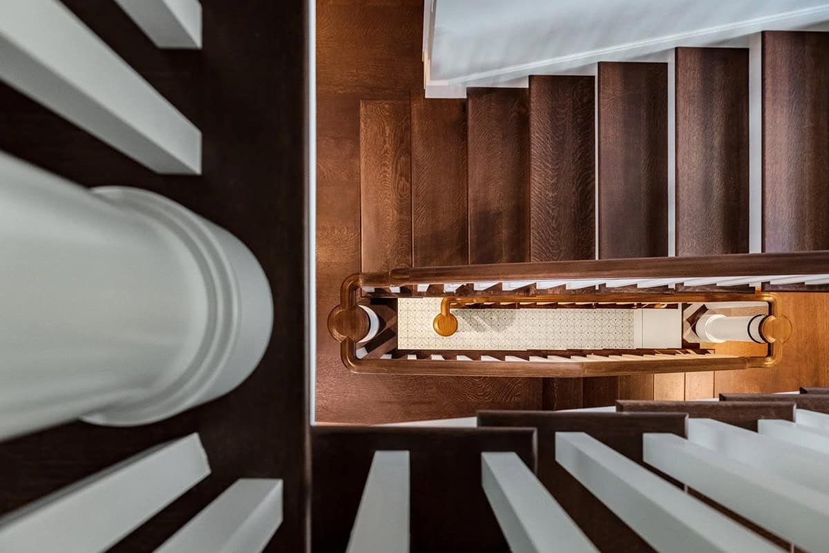 Bird's-eye view of a curved wood staircase with brass balusters