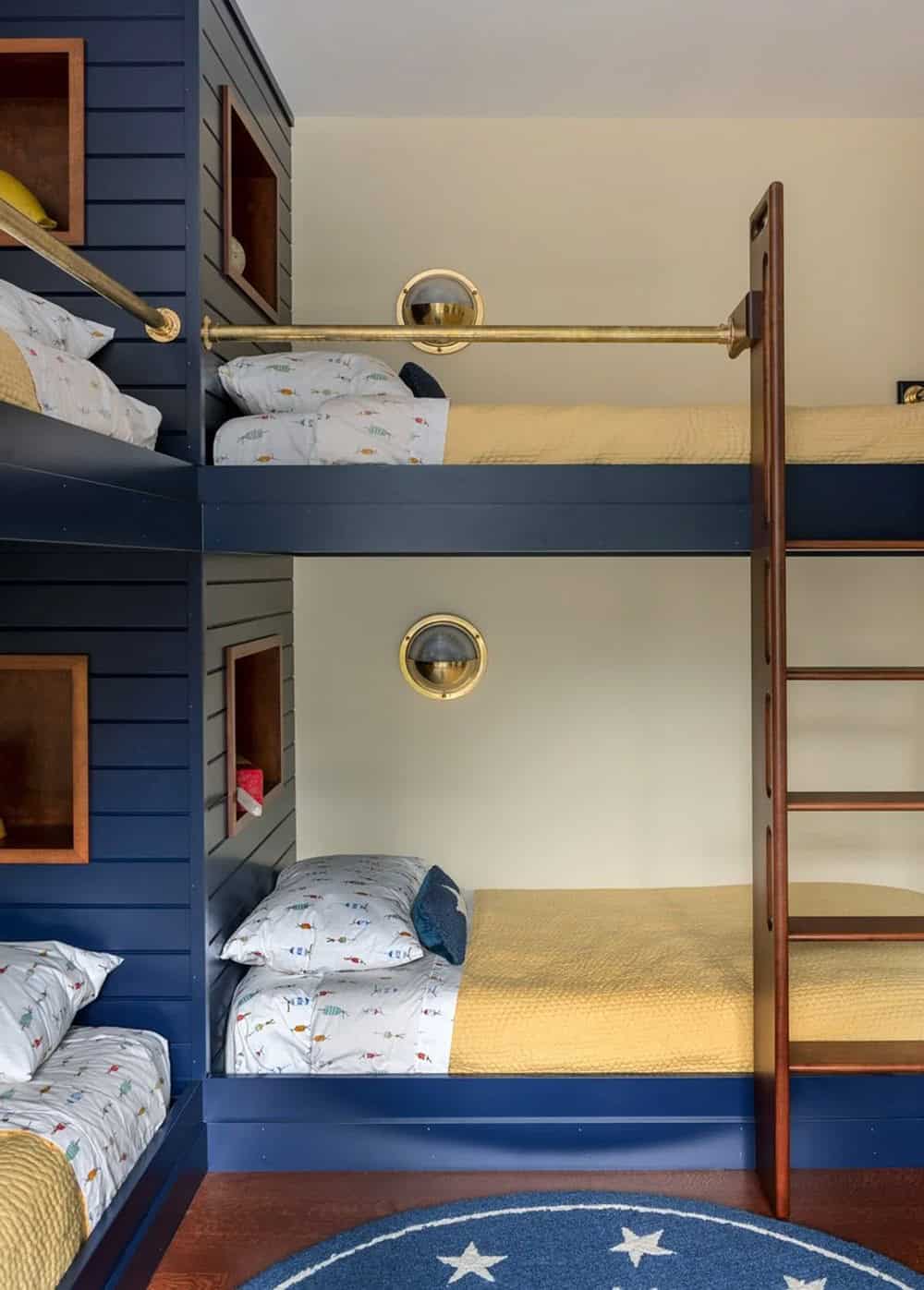 Built-in navy bunk beds with brass ladder and porthole sconces