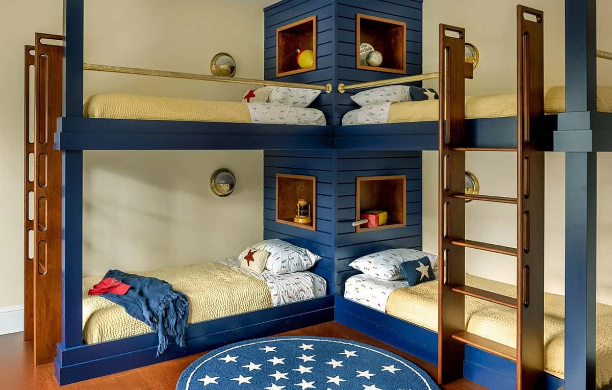Corner-built navy bunk beds with brass rails, portholes, and star rug
