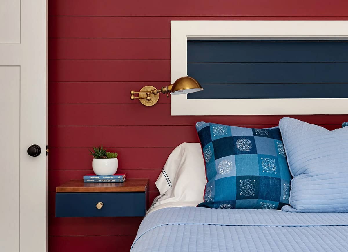Red shiplap bedroom nook with brass sconce and floating nightstand