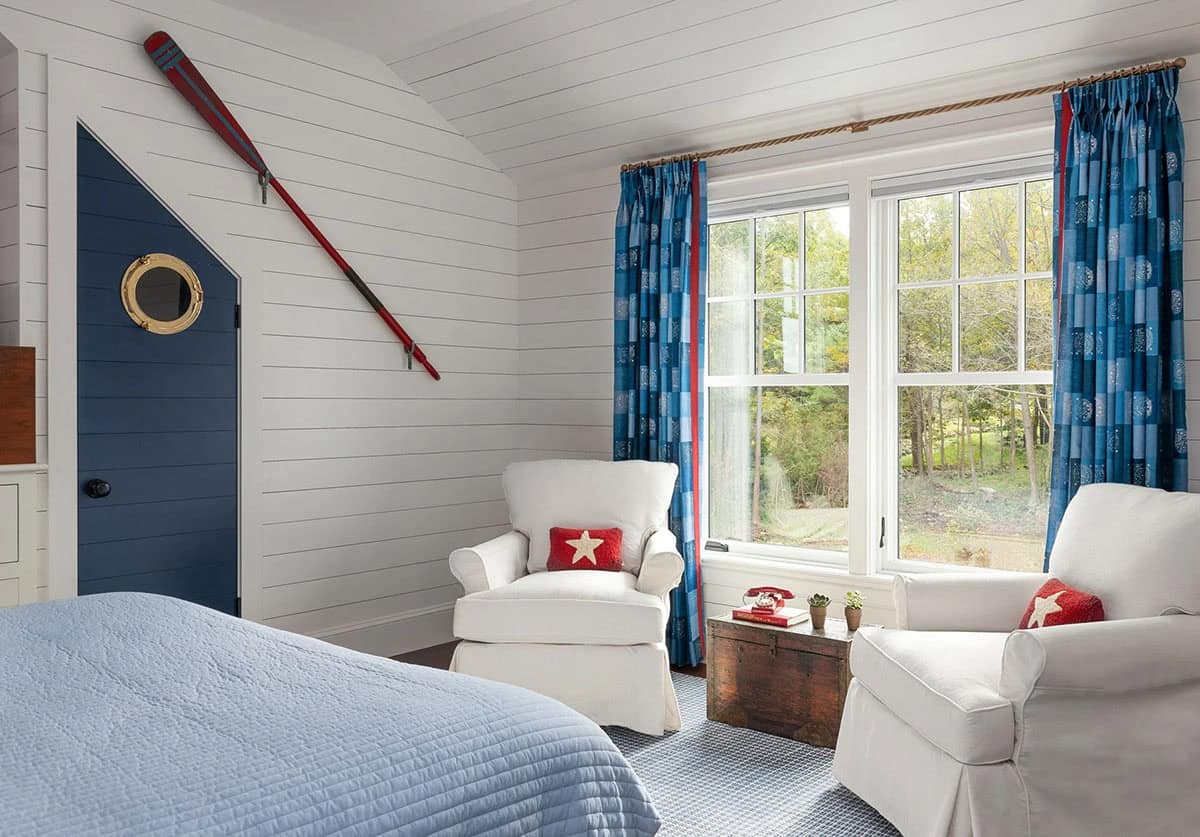 Kids' bedroom with white armchairs, red oar decor, and blue plaid curtains