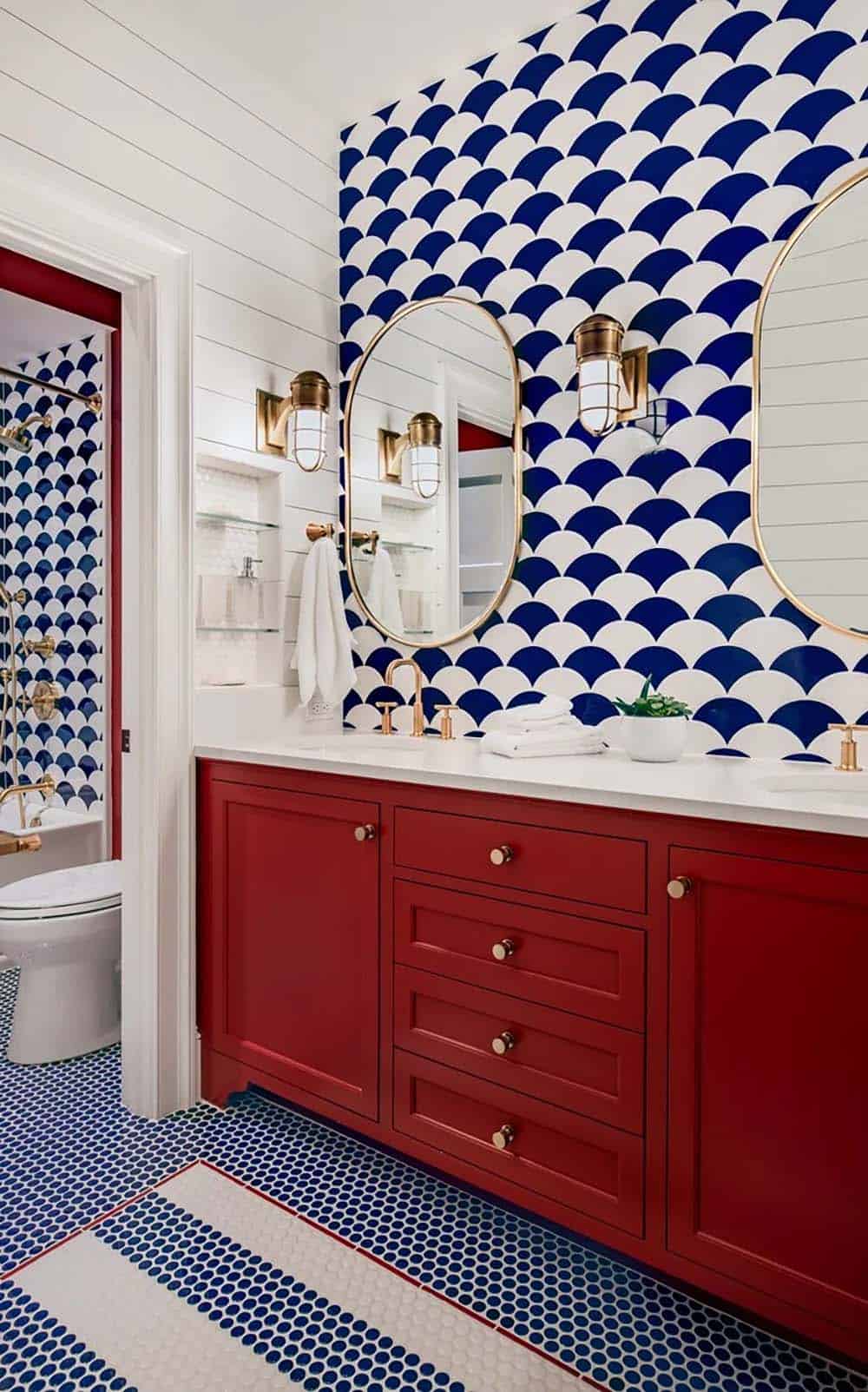 Bathroom with navy scallop wallpaper, red vanity, and brass fixtures