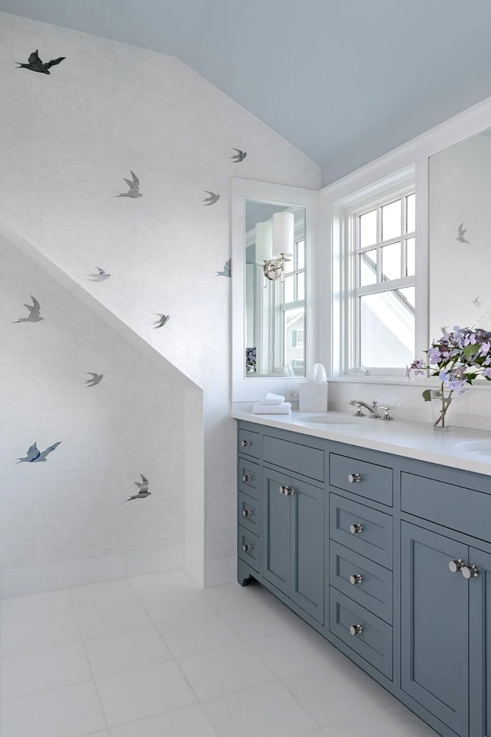 Bathroom under eaves with bird-print wallpaper and blue vanity